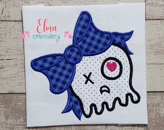 Op de afbeelding: Borduurwerk van een geest met een blauw-wit geruite strik, een roze hart als oog en de letters "XO" op zijn gezicht.