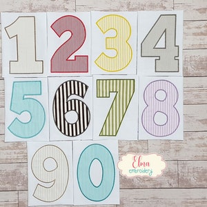 May include: Ten colorful numbers, 1 through 10, with a striped pattern. Each number is on a separate white card. The cards are arranged in two rows on a wooden surface.