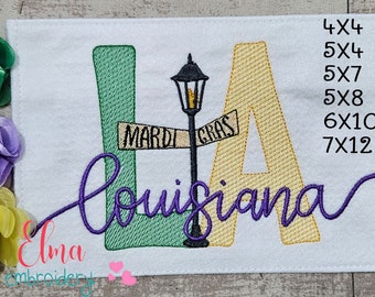 May include: Embroidered design of the letters "LA" with a street sign that reads "Mardi Gras" and a street lamp in between the letters. The word "Louisiana" is embroidered in a cursive font below the letters. The design is available in sizes 4x4, 5x4, 5x7, 5x8, 6x10, and 7x12 inches.