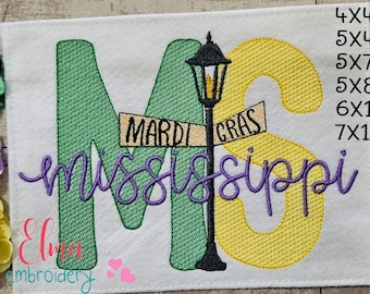 May include: Embroidered design of the letters "MS" with a street sign that reads "Mardi Gras" and the word "mississippi" in purple cursive. The letters are green and yellow. The design is available in sizes 4x4, 5x4, 5x7, 5x8, 6x10, and 7x12 inches.