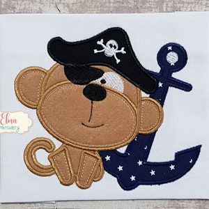 May include: Embroidered patch of a brown monkey wearing a black pirate hat with a white skull and crossbones design. The monkey has a black eye patch and is holding a blue anchor with white stars.