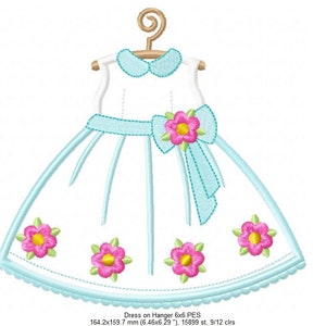 May include: A white dress with a blue sash and pink flowers embroidered on the skirt. The dress is on a hanger and has a scalloped hem.