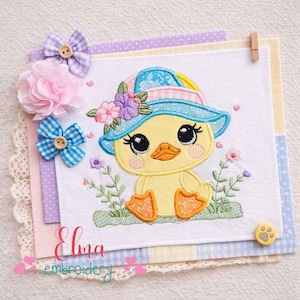 May include: An embroidered duckling wearing a blue hat decorated with flowers, sitting amongst embroidered greenery and flowers. The duckling is yellow with orange feet and beak. The image includes decorative bows and the text "Elma embroidery".