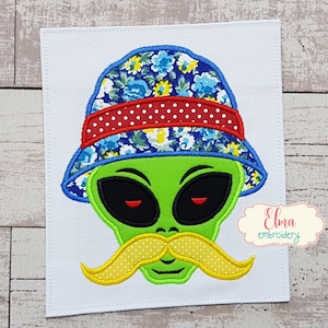 May include: Green alien face with a yellow mustache wearing a blue and white floral bucket hat with a red and white polka dot band.