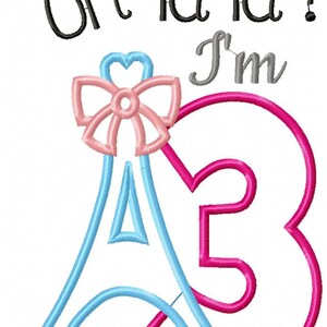 K&ouml;nnte beinhalten: Ein Stickdesign mit dem Text "oh la la ! I'm" in Schwarz und Grau. Unter dem Text befindet sich eine hellblaue Eiffelturm-Kontur mit einer rosa Schleife an der Spitze, verschlungen mit einer gro&szlig;en, kr&auml;ftigen rosa Zahl 3 mit einem kleinen rosa Herz.