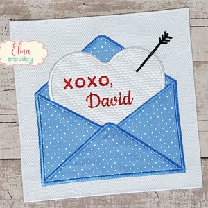 Peut inclure: Une enveloppe bleue à pois blancs avec un cœur blanc sur lequel est inscrit le texte "XOXO, David". Le cœur est traversé par une flèche.