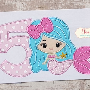 Puede incluir: Diseño bordado de un número 5 de lunares rosa y blanco con una sirena sosteniendo una estrella de mar. La sirena tiene el pelo azul, un lazo rosa y una cola rosa.
