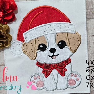 Può includere: Disegno ricamato di un cucciolo bianco che indossa un cappello di Babbo Natale rosso con un bordo bianco e un fiocco rosso. Il design è disponibile nelle dimensioni 4x4, 5x5, 6x6 e 7x7 pollici.
