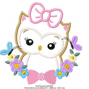 May include: Embroidered design of a white owl with pink bow and a floral wreath. The owl has large black eyes and a yellow beak. The wreath is made of blue, yellow, and purple flowers with green leaves. Two butterflies are on either side of the owl, one blue and one purple.