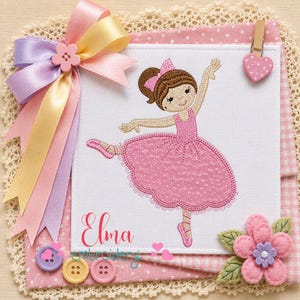 May include: A square white fabric panel featuring an embroidered ballerina in a pink polka-dot tutu, with the name Elma embroidered in red script. The panel is decorated with a multi-colored satin ribbon bow, three buttons, and a felt flower.