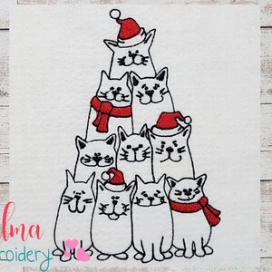 May include: A Christmas tree made of white cats wearing red Santa hats and scarves. The cats are arranged in a pyramid shape with the top cat wearing a Santa hat.