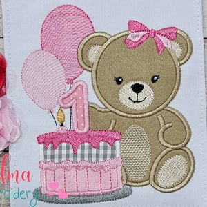 May include: Embroidered design featuring a teddy bear with a pink bow, a birthday cake with a number one candle, and pink balloons. The design is on a white background, with the text "Elma embroidery" at the bottom.