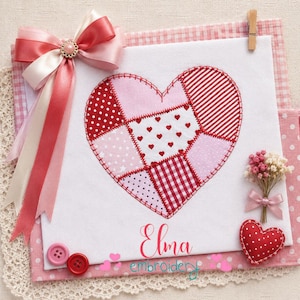 May include: A white fabric square featuring a patchwork heart design in shades of red and pink with various patterns including polka dots, stripes, and gingham. A multi-layered pink and white ribbon bow, two pink buttons, and a small heart ornament.