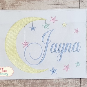 May include: A white embroidered design with a yellow crescent moon and blue stars. The name "Jayna" is embroidered in blue cursive script.