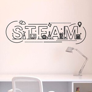 May include: Black line art wall decal spelling out "STEAM" with related icons. The design includes a sun, cloud, factory, computer, gear, guitar, pencils, ruler, lightbulb, and calculator. A white desk and lamp are in the foreground.
