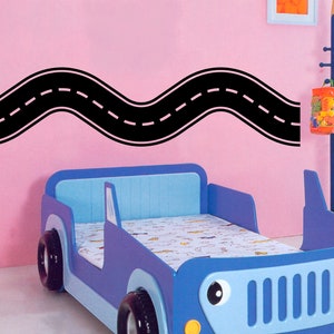 May include: A blue and white car-shaped bed with a black road sticker on a pink wall. The bed has a white and blue patterned mattress.