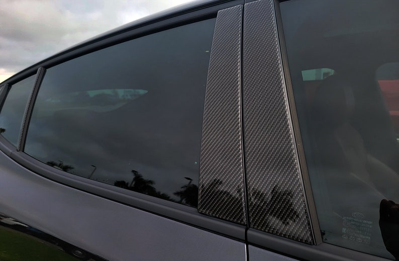 Pu&ograve; includere: Primo piano del lunotto posteriore di un'auto con finitura in fibra di carbonio nera. La finitura &egrave; realizzata in materiale intrecciato con finitura nera.