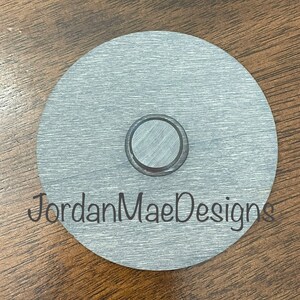 Peut inclure: Un disque rond en m&eacute;tal argent&eacute; avec une d&eacute;coupe circulaire plus petite au centre. Le disque a une finition bross&eacute;e et le texte "JordanMaeDesigns" est imprim&eacute; en bas.