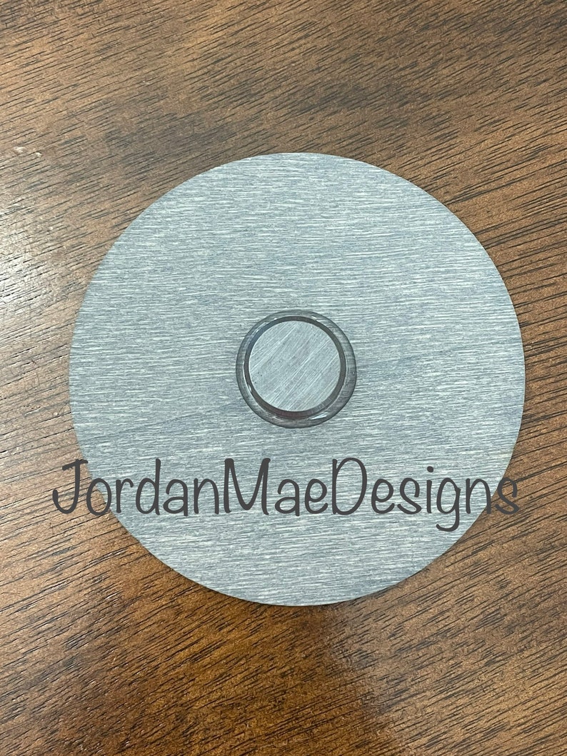 Peut inclure: Un disque rond en m&eacute;tal argent&eacute; avec une d&eacute;coupe circulaire plus petite au centre. Le disque a une finition bross&eacute;e et le texte "JordanMaeDesigns" est imprim&eacute; en bas.