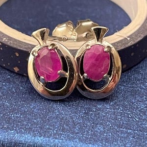 May include: A pair of silver earrings with pink oval-shaped gemstones set in a delicate silver frame.