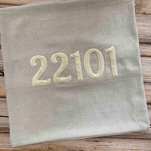 May include: A light gray throw pillow with the number 22101 embroidered in white.