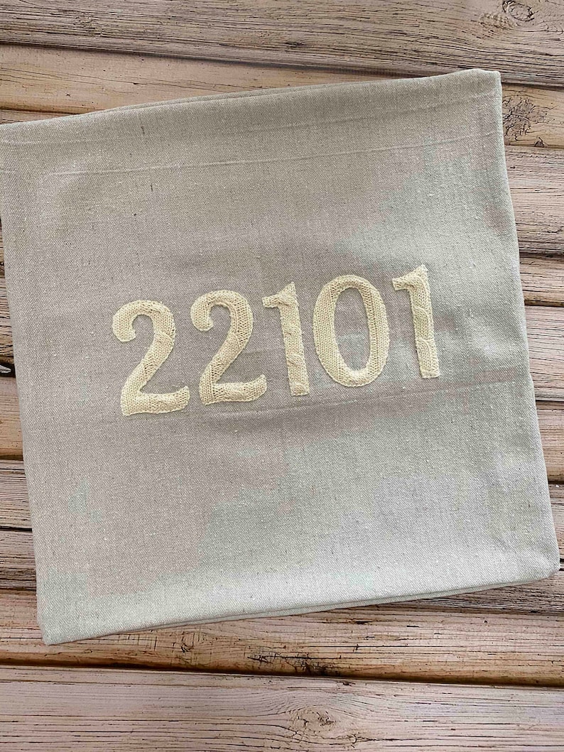May include: A light gray throw pillow with the number 22101 embroidered in white.