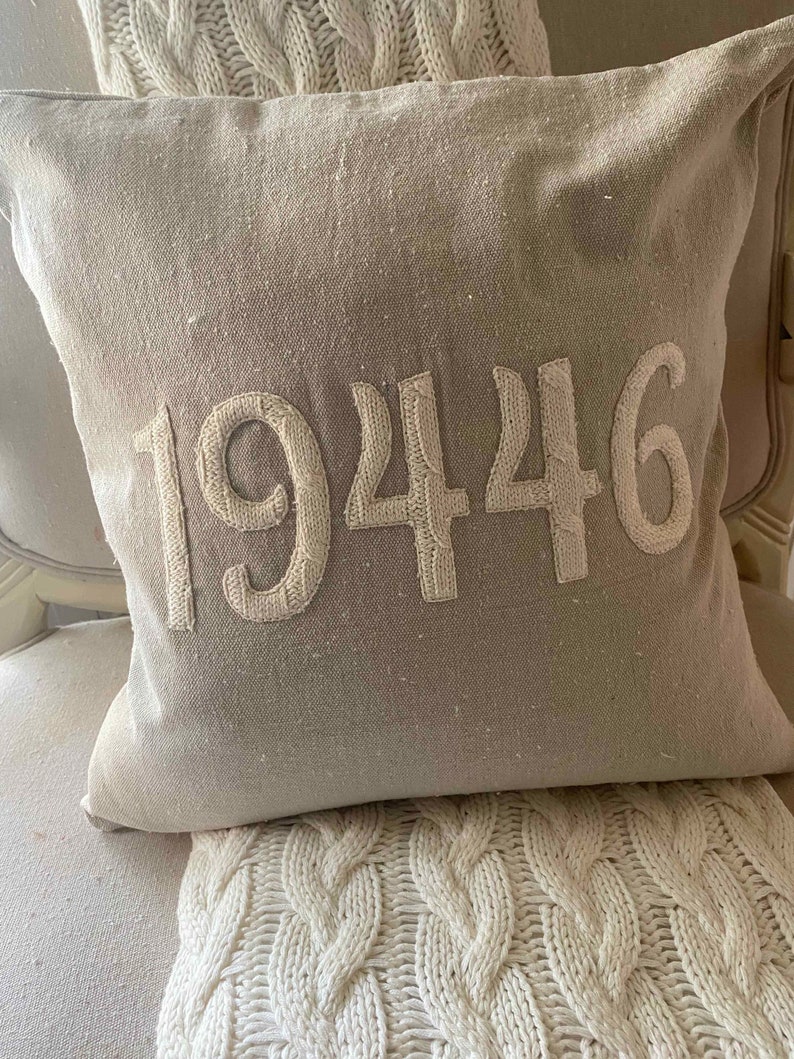 May include: A beige throw pillow with the number 19446 embroidered in white on the front.