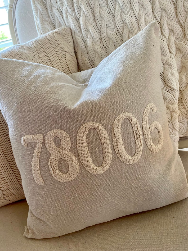 May include: A beige throw pillow with the number 78006 embroidered in white on the front.