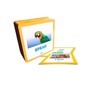 Puede incluir: Un mont&oacute;n de tarjetas did&aacute;cticas con borde amarillo. Una tarjeta muestra un loro colorido con la palabra "SPEAK" en azul. Otra tarjeta muestra las palabras "DO", "DID", "DONE" y "TAKE" con una imagen de un coche.