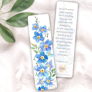 May include: A bookmark with a watercolor illustration of blue forget-me-not flowers. The bookmark features a Bible verse from Philippians 4:6-7, "Do not be anxious about anything, but in everything by prayer and supplication with thanksgiving, let your requests be made known to God. And the peace of God, which surpasses all understanding, will guard your hearts and your minds in Christ Jesus."