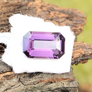 May include: A purple gemstone with a rectangular emerald cut.
