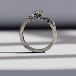 May include: A silver ring with a wave design. The wave is sculpted in detail and appears to be crashing over the band of the ring.