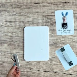 May include: White rectangular car air vent phone holder with a metal clip, and two white rectangular cards. One card has a photo of a child wearing bunny ears and the text "Drive Safe Daddy, We love you!"