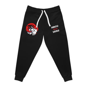 Può includere: Pantaloni della tuta neri con un logo di ariete rosso e bianco e il testo "HBCU Since 1892" sulla gamba destra.