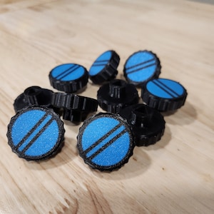 May include: A group of ten blue and black plastic knobs with a textured surface. The knobs have a raised design of two parallel lines on the top.