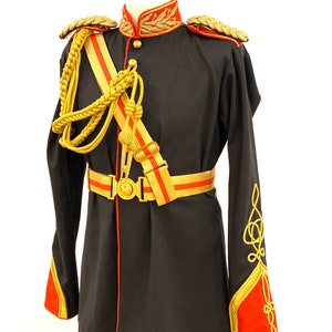 Może przedstawiać: Czarny mundur wojskowy z złotymi i czerwonymi ozdobami. Mundur ma wysoki kołnierz, długie rękawy i pasek ze złotą klamrą. Rękawy mają złote sznury i czerwone mankiety. Mundur jest na manekinie.