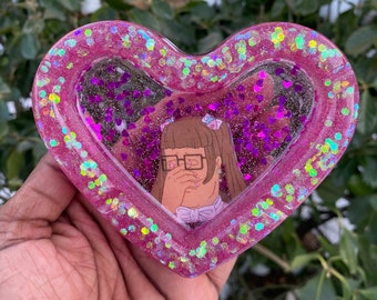 Cenicero de resina con forma de corazón llorón de color rosa.