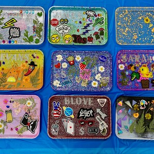 Puede incluir: Nueve bandejas decorativas con diferentes dise&ntilde;os y colores. Las bandejas est&aacute;n hechas de resina y tienen un acabado brillante. Algunas bandejas tienen flores y hojas prensadas, mientras que otras tienen pegatinas y otros adornos. Las bandejas son de diferentes tama&ntilde;os y formas.