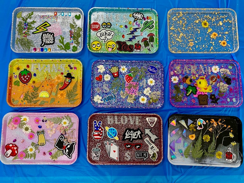 Puede incluir: Nueve bandejas decorativas con diferentes dise&ntilde;os y colores. Las bandejas est&aacute;n hechas de resina y tienen un acabado brillante. Algunas bandejas tienen flores y hojas prensadas, mientras que otras tienen pegatinas y otros adornos. Las bandejas son de diferentes tama&ntilde;os y formas.