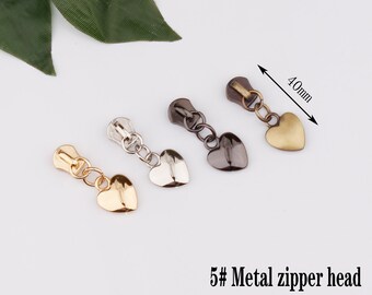 May include: Four metal zipper pulls in gold, silver, black, and bronze. Each pull features a heart-shaped charm and a chain. The zipper pulls are 40mm long. 5# Metal zipper head.