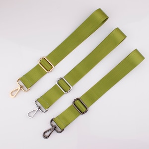 May include: Three green adjustable straps with metal clasps. The straps are made of a woven fabric and have a matte finish. The clasps are silver, gold, and black.