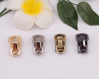 May include: Four metal clasps in different finishes: gold, silver, brass, and black. Each clasp has a square frame with a round ring at the bottom.
