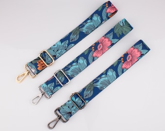 Pode incluir: Três correias ajustáveis com estampa floral e fechos de metal. As correias são azuis com desenhos florais rosa e verdes.