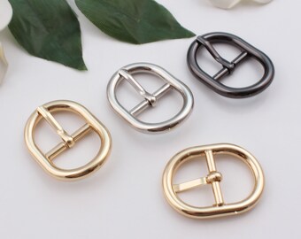 May include: Four oval-shaped metal belt buckles in gold, silver, and black.