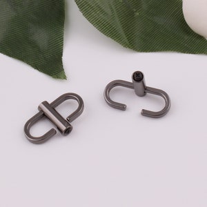 May include: Two black metal swivel hooks with a screw closure. The hooks are designed for attaching to a bag or other item.