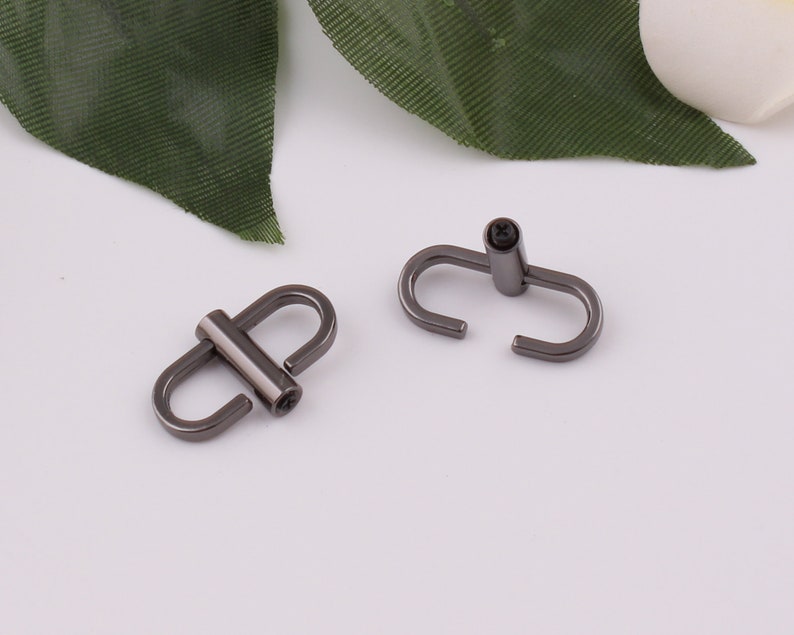 May include: Two black metal swivel hooks with a screw closure. The hooks are designed for attaching to a bag or other item.