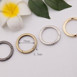 May include: Four metal key rings with a spring-loaded clasp. The rings are 38 mm in diameter and 5.5 mm wide. The rings are in gold, silver, and black.