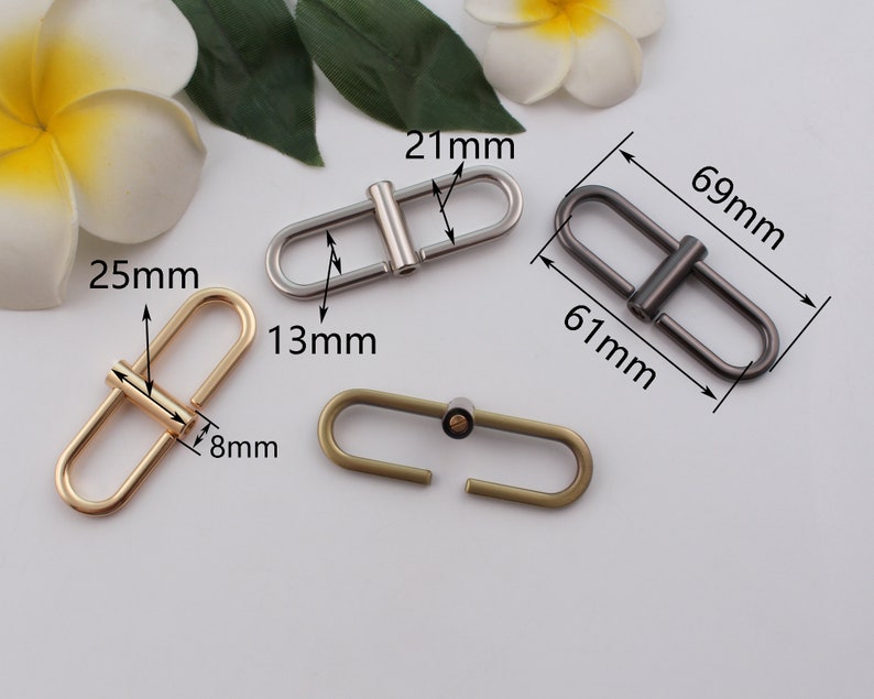 May include: Three metal D-ring clasps in gold, silver, and bronze. The gold clasp measures 25 mm by 13 mm, the silver clasp measures 69 mm by 61 mm, and the bronze clasp measures 21 mm by 8 mm.