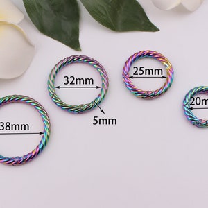 Pode incluir: Quatro argolas de chave de metal de diferentes tamanhos com cores arco-íris. Os anéis têm um diâmetro de 20 mm, 25 mm, 32 mm e 38 mm. Os anéis têm uma largura de 5 mm.
