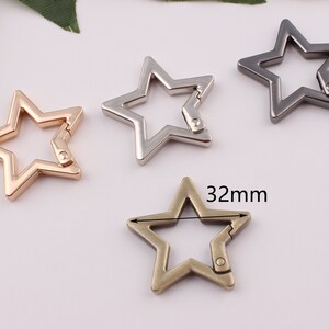 Puede incluir: Cuatro cierres de metal en forma de estrella en oro, plata y bronce. Los cierres miden 32 mm.